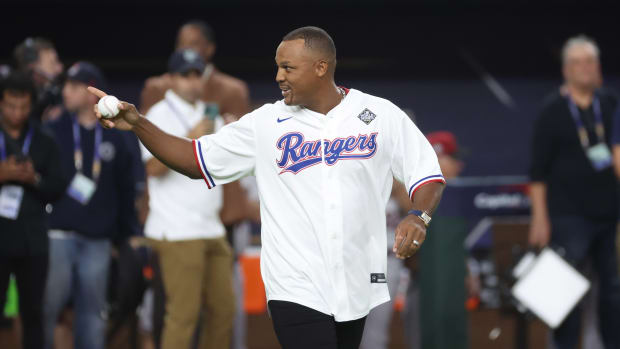 Adrián Beltré points to the side and smiles holding a baseball
